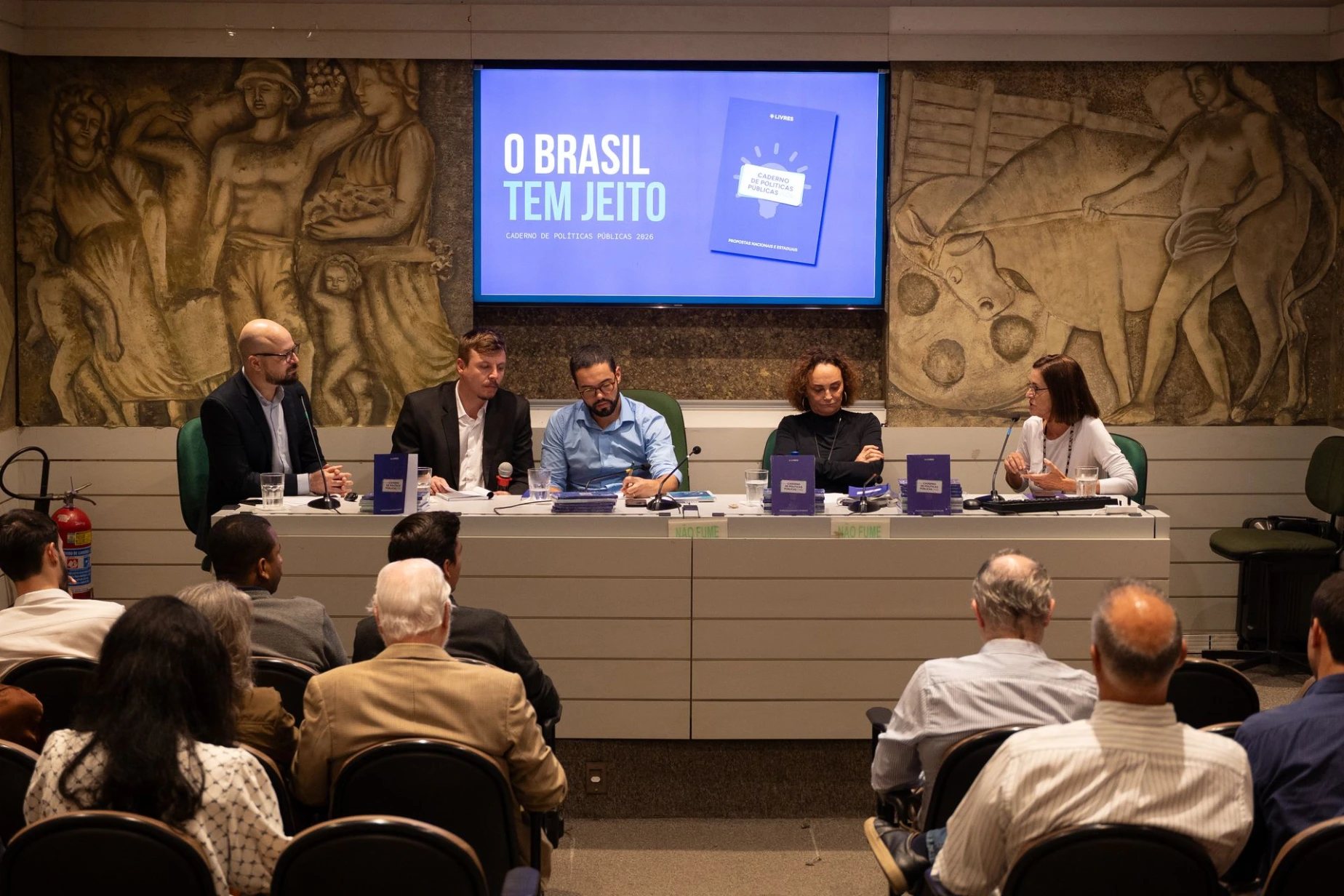 Sandra Rios, Elena Landau, Magno Karl, Pedro Duarte e Helio Secco em mesa com painel do Caderno de Políticas Públicas